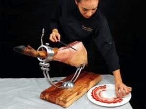 Chef slicing ham at upscale event venue Sala Sambara 81 for interactive culinary experience.