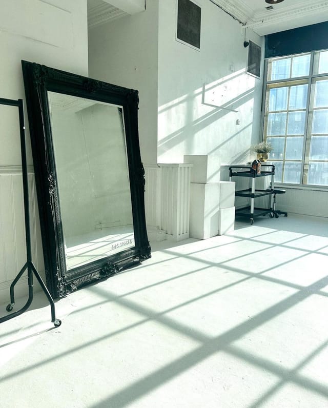 Bright minimalist event space with large mirror, ideal for gatherings and workshops.