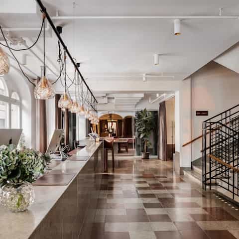 Modern lobby at Bar in Miss Clara, featuring warm lighting and greenery for events.