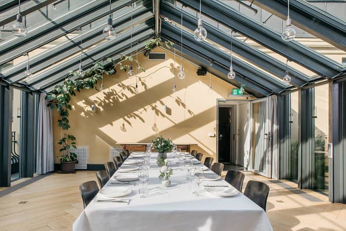 Elegant event space at Miss Clara by Nobis with a long table under a glass roof.