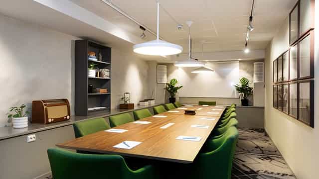 Modern meeting room at Elite Hotel Adlon with wooden table and green chairs for workshops.