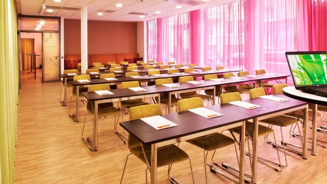 Well-lit meeting room with modern tables, ideal for workshops and training sessions.