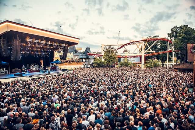 Vibrant outdoor concert at Gröna Lund with enthusiastic crowd and illuminated stage.