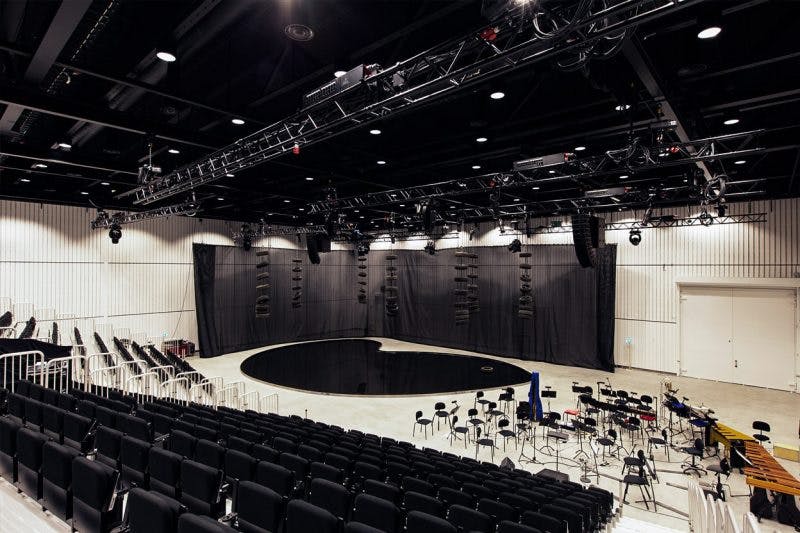 Artbox Event Hall with black stage and tiered seating for conferences and performances.