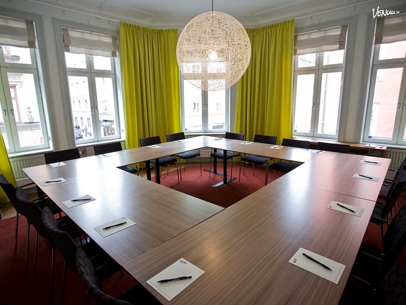Modern meeting room with U-shaped table and bright yellow curtains for collaboration.
