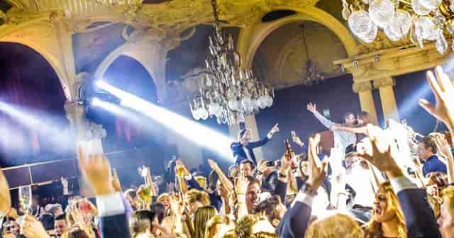 Vibrant nightclub scene at Café Opera with elegant chandeliers and lively celebration.