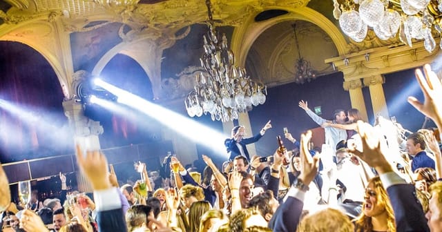 Vibrant nightclub scene at Café Opera with elegant chandeliers and lively celebration.