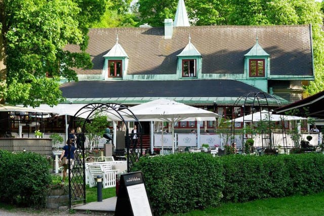 Charming outdoor venue at Villa Godthem with rustic building and lush greenery.