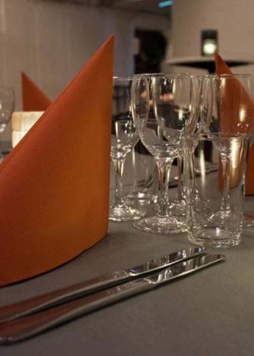 Elegant dining table with glassware and orange napkins for formal events.