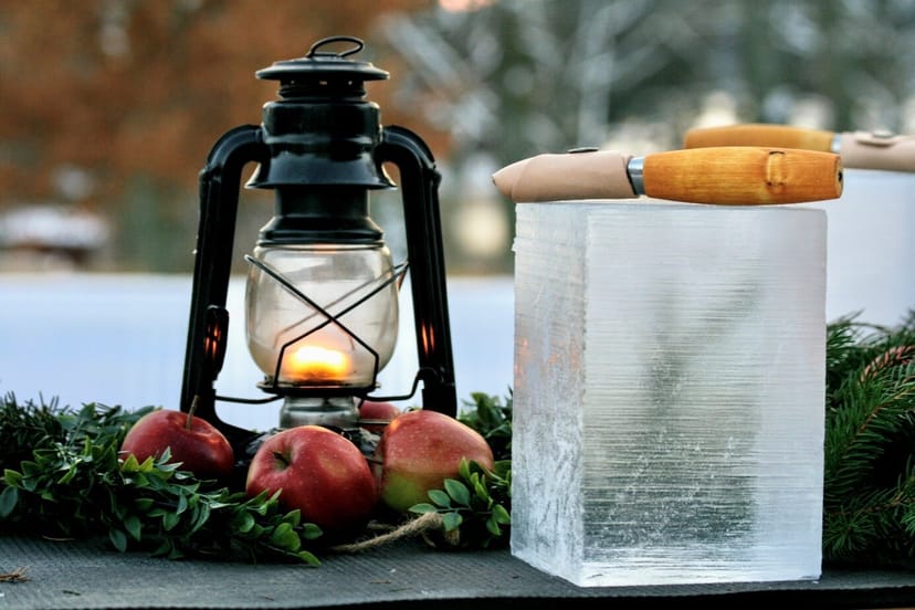 Rustic outdoor event setup at Kvarnbacken with vintage lantern, apples, and ice centerpiece.