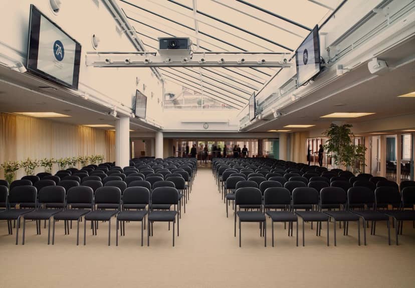 Spacious conference venue with black chairs, ideal for corporate events and presentations.