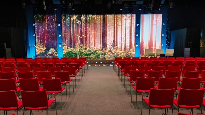 Conference room with red chairs and forest backdrop for corporate events at Elite Hotel Marina Tower.