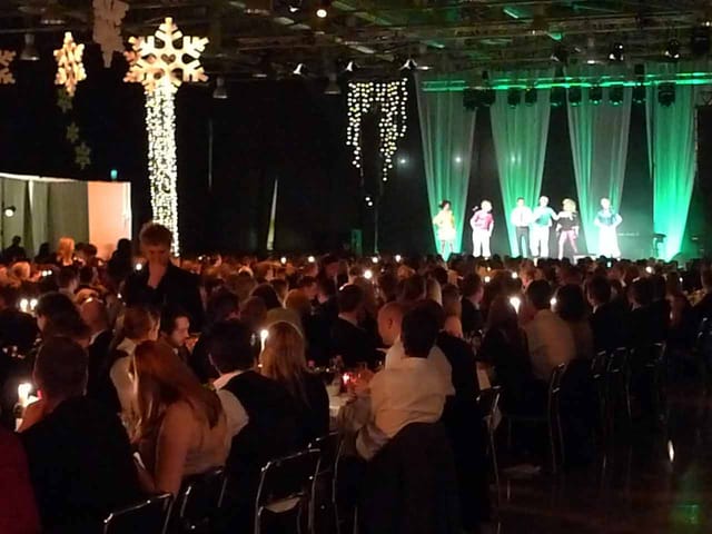 Live music gala at Magasin 9 with elegant candlelit tables and vibrant green stage lighting.