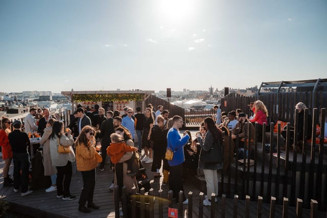 Vibrant rooftop networking event at Urban Deli with greenery and sunny ambiance.