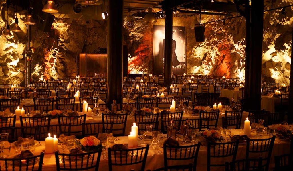 Elegant event space with candlelit tables and dramatic rock walls for upscale gatherings.