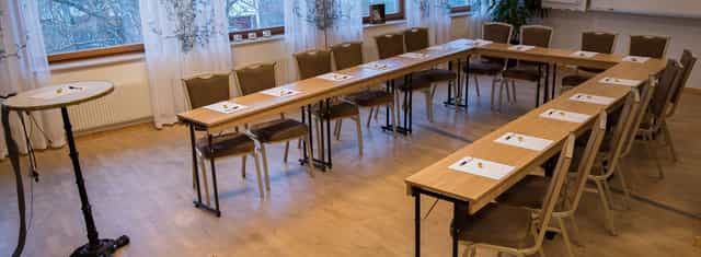 Conference center meeting room with long tables, ideal for workshops and strategy sessions.