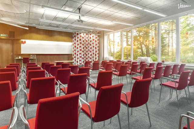 Well-lit meeting room with red chairs for workshops and seminars at Skogshem & Wijk.