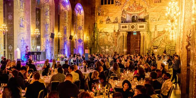 Blå hallen in Stockholm City Hall, elegant dinner event with floral centerpieces.