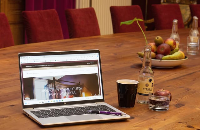 Meeting room at Hotel Hellsten with laptop, coffee, and fresh fruit for events.