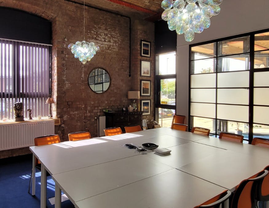 Modern conference room with large white table and orange chairs, perfect for workshops.