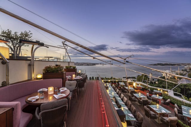 Rooftop restaurant at Swissotel with elegant seating and stunning water views at dusk.