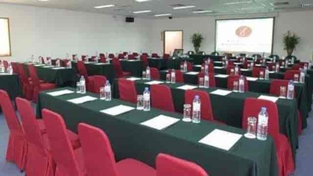 Meeting room with green tables and red chairs, perfect for conferences and workshops.