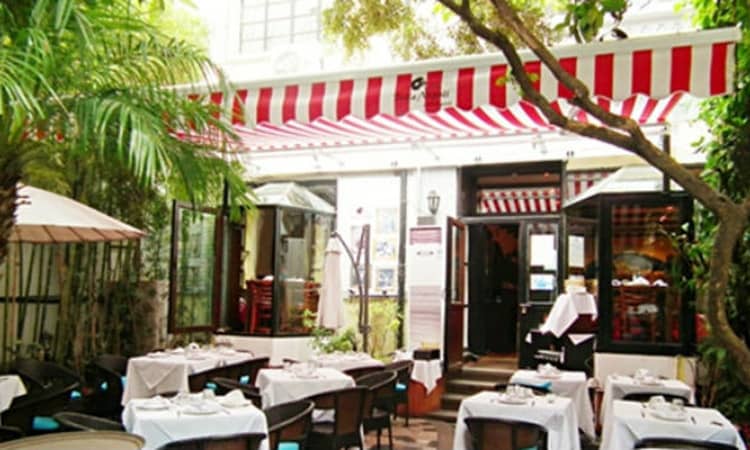 Charming outdoor dining area at Bella Napoli with striped awning for events.