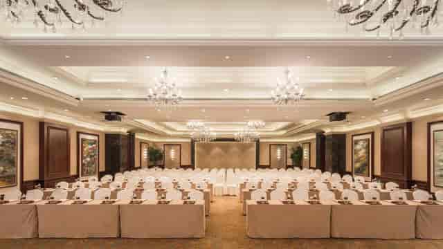 Elegant W Hotels ballroom set for corporate event with white-covered tables and chandeliers.