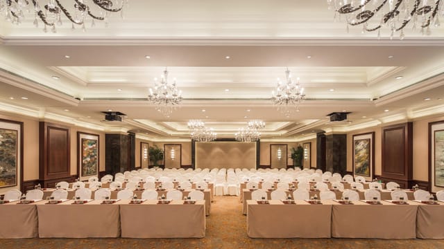 Elegant W Hotels ballroom set for corporate event with white-covered tables and chandeliers.