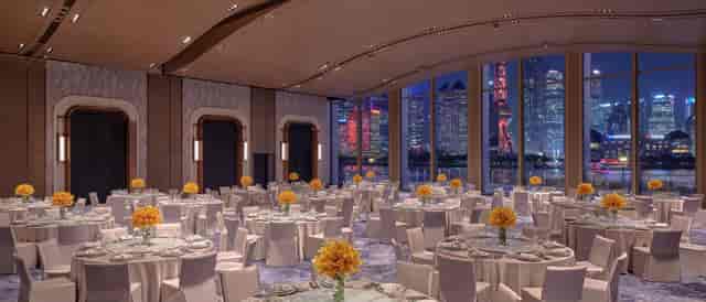 Elegant ballroom with floral centerpieces and skyline view for corporate events or galas.