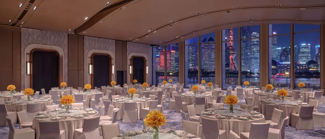 Elegant ballroom with floral centerpieces and skyline view for corporate events or galas.