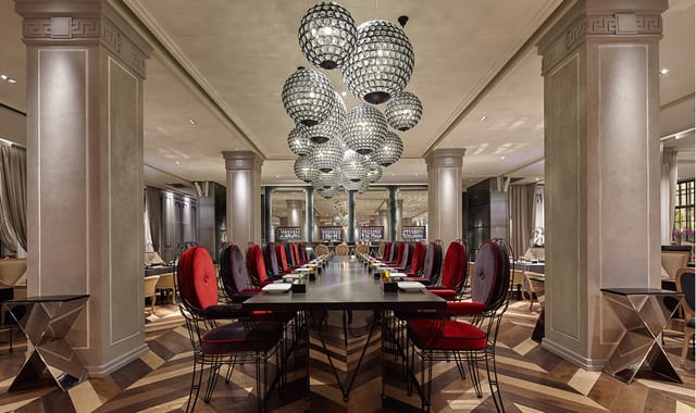 Elegant dining area with long table, plush red chairs for corporate events.
