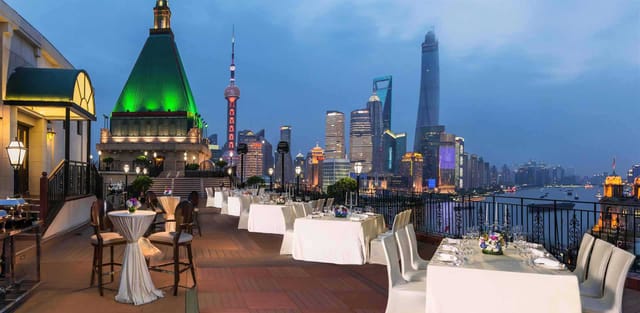 Rooftop terrace at Fairmont Peace Hotel, elegant tables with city skyline for upscale events.