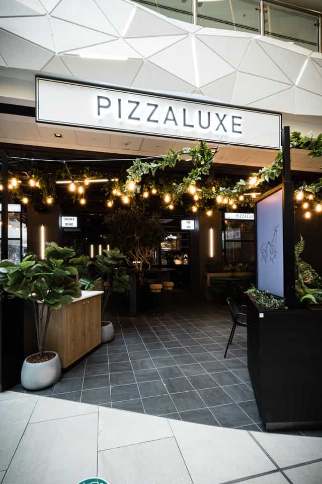 Stylish event space at PizzaLuxe Manchester with lush greenery, perfect for networking events.