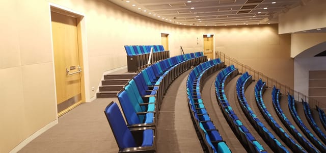 Modern Sands Theatre auditorium with tiered blue seating for presentations and lectures.