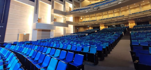 Sands Theatre auditorium with tiered seating and vibrant blue chairs for events.