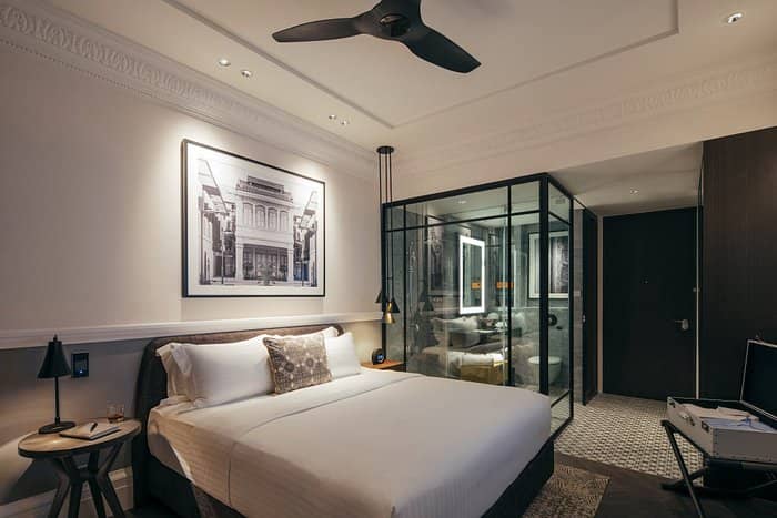 Modern hotel room with glass-enclosed bathroom, perfect for events and business travelers.