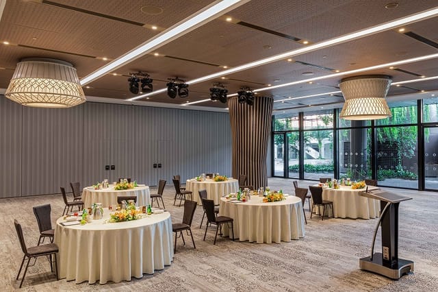 Elegant event space at The Commune, featuring round tables for meetings and banquets.