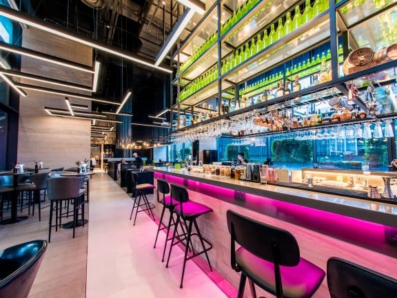 Modern bar in YOTEL Singapore, vibrant lighting for networking events and casual meetings.