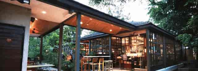 Charming cafe with glass walls and lush greenery, perfect for events and gatherings.