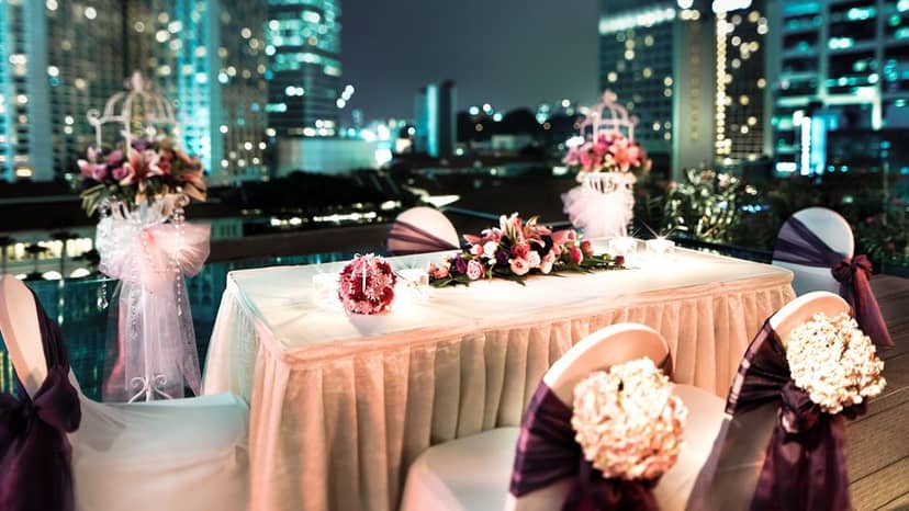 Elegant outdoor wedding venue at Naumi Hotel Singapore with floral decor and city lights.