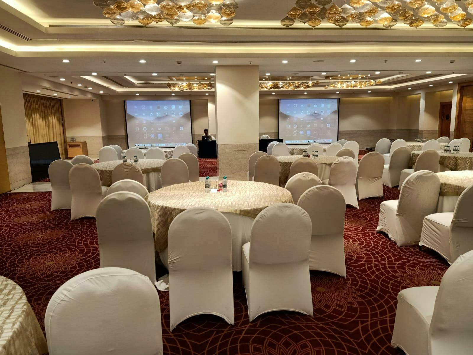 Event space at Lemon Tree Hotel Gurugram with elegant round tables for conferences.