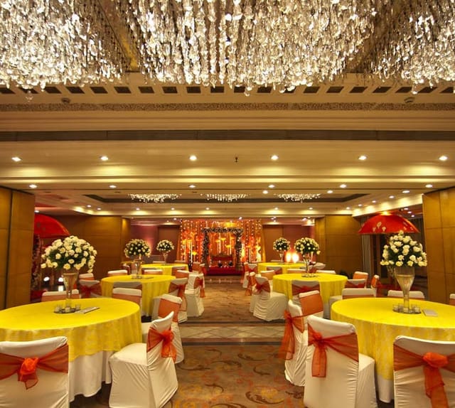 Banquet Hall at Jaypee Siddharth with yellow tables, ideal for weddings and celebrations.