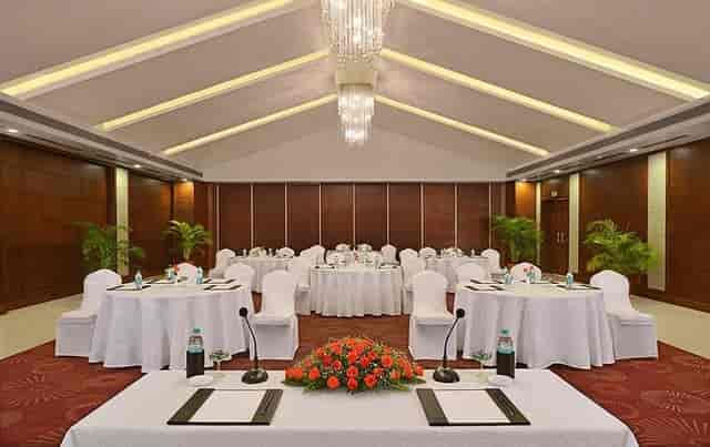 Conference hall with round tables and floral decor at Country Inn & Suites. Ideal for workshops.