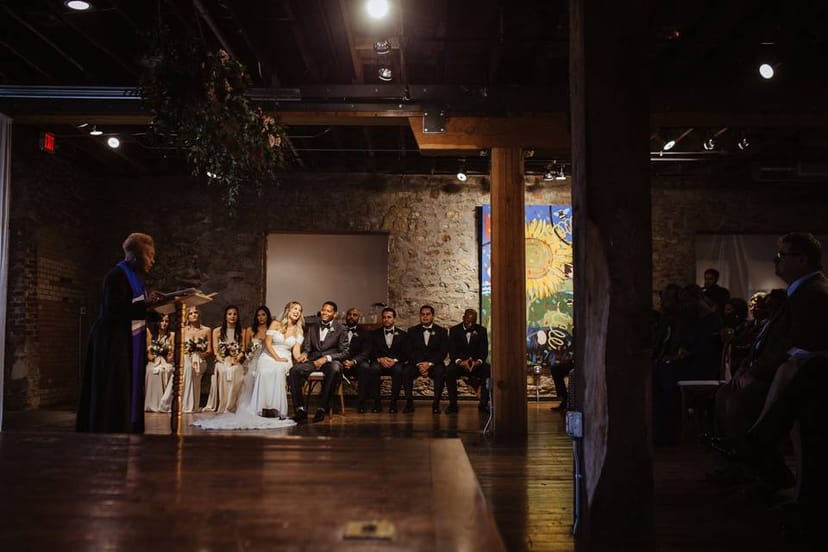 Rustic wedding ceremony at Fine Arts Gallery with floral decor and warm lighting.