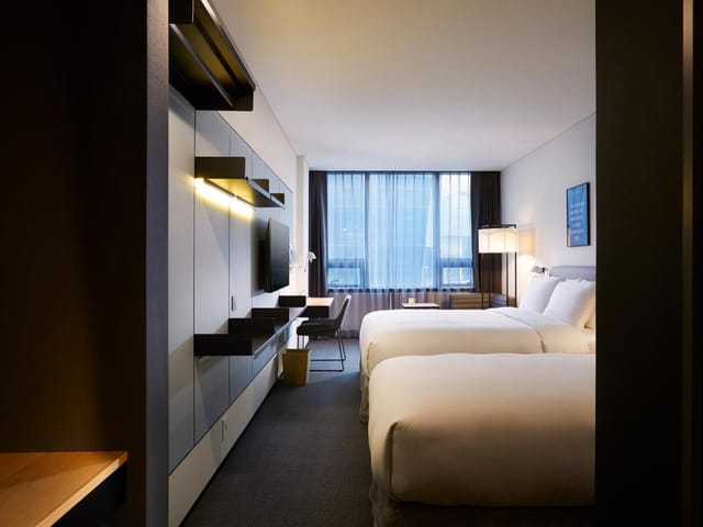 Modern hotel room with twin beds, ideal for business events and comfort.