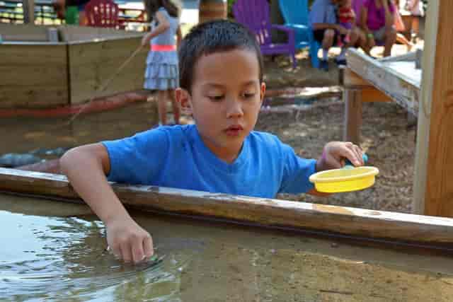 Child enjoying hands-on activity at Imagine Acres outdoor family event.