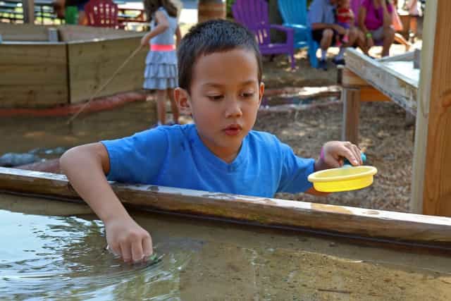 Child enjoying hands-on activity at Imagine Acres outdoor family event.