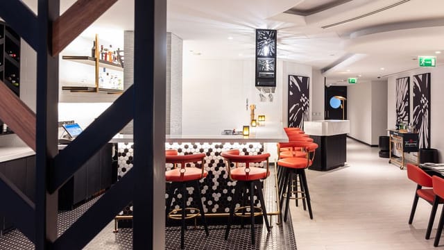Modern bar area with red stools at Rose Rayhaan, ideal for networking events and gatherings.