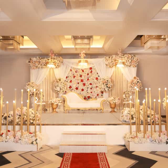 Elegant conference hall stage with floral backdrop, ideal for weddings and upscale events.